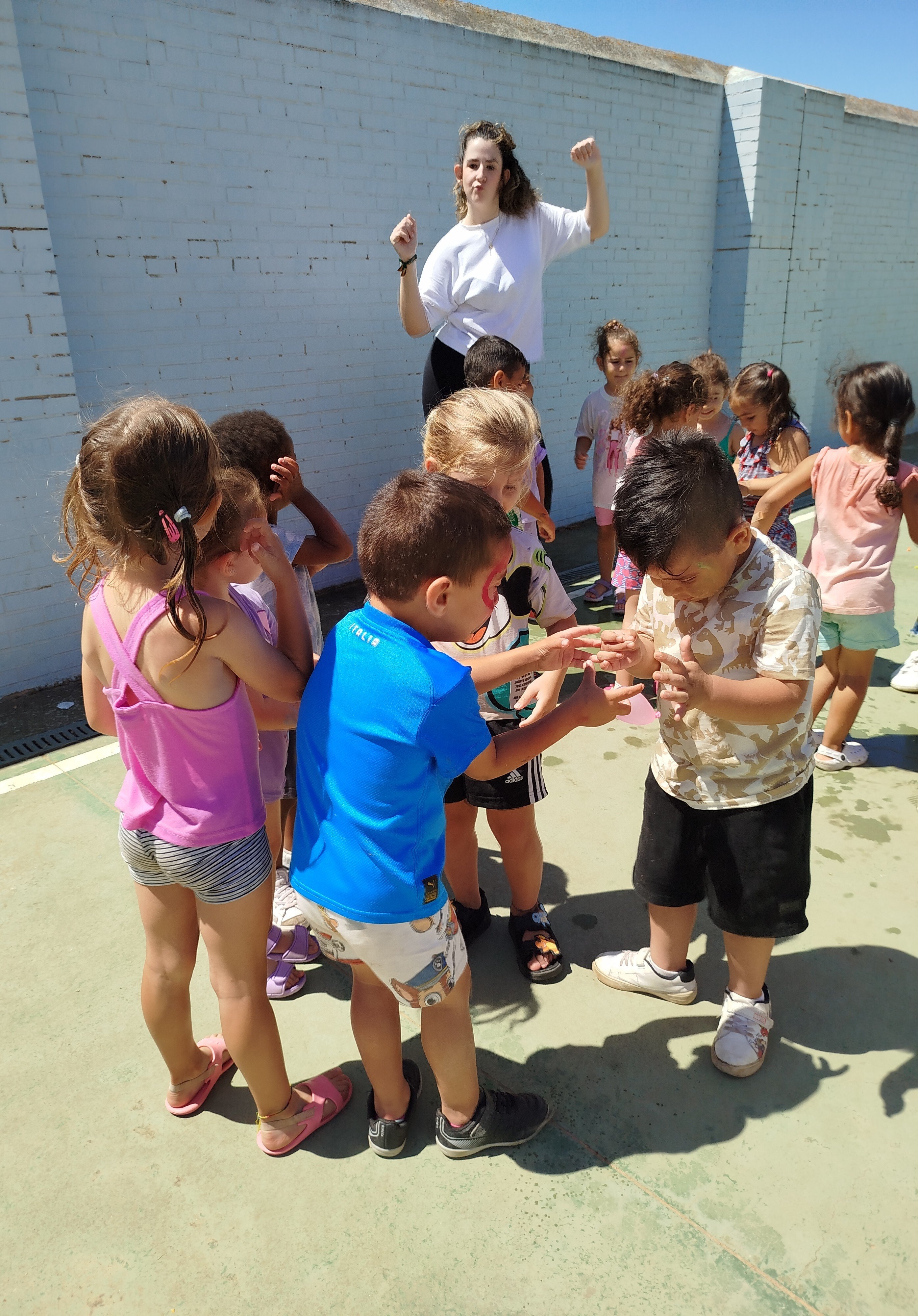 Niños participando en actividades grupales al aire libre bajo la supervisión de una monitora. Juegos con globos de agua.